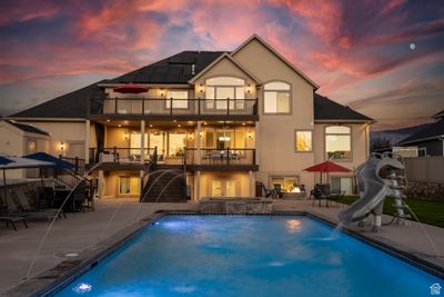 Rear view of the home highlighting the pool, slide, hot tub, fire pit, decks, & patio. | Image 1