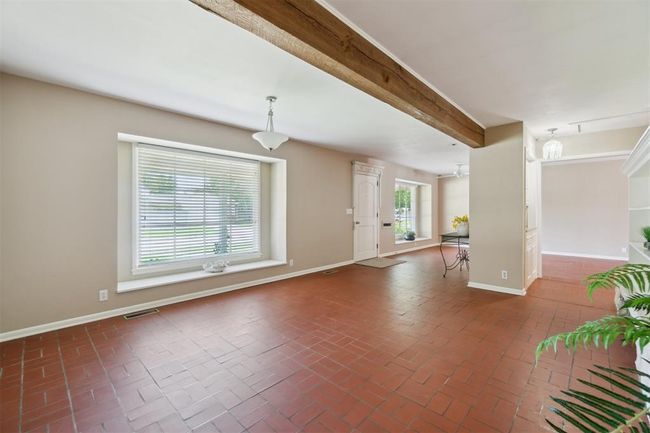 Unfurnished living room featuring brick floors and beamed ceiling | Image 9