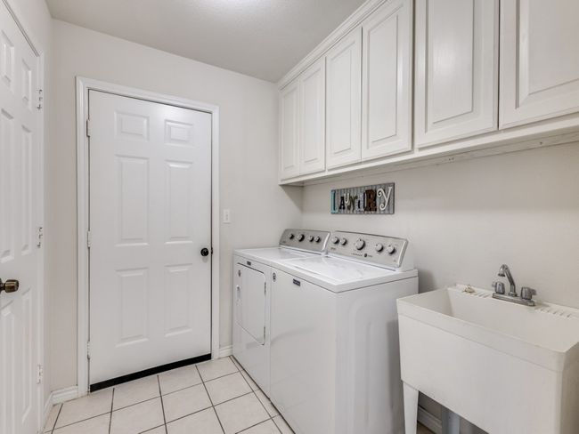 Laundry room featuring cabinet space, washing machine and clothes dryer, light tile patterned floors, and baseboards | Image 23