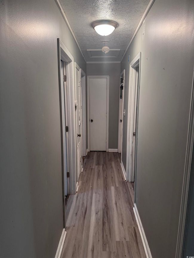Corridor with a textured ceiling, wood finished floors, and baseboards | Image 10