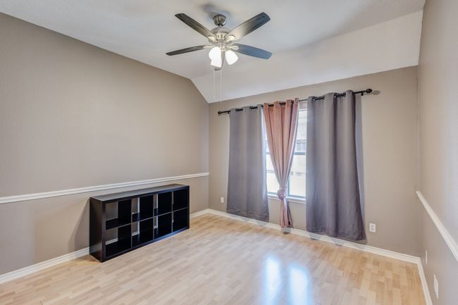 Empty room with wood finished floors, a ceiling fan, lofted ceiling, and baseboards | Image 5