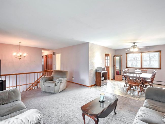 Carpeted living room featuring ceiling fan with notable chandelier | Image 15
