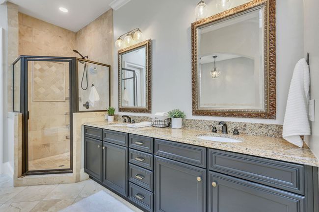 The bath boasts a double sink vanity, upgraded recessed lighting and a tiled shower with glass doors. | Image 31