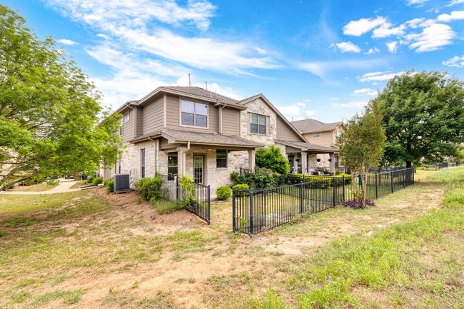 View of front facade with fence, a front lawn, stone siding, and central air condition unit | Image 28