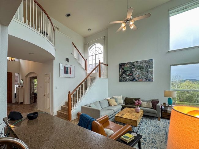 Living area with a towering ceiling, arched walkways, stairs, and ceiling fan | Image 11