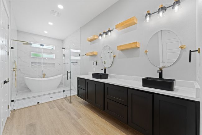 Full bathroom featuring double vanity, a marble finish shower, wood finished floors, and a sink | Image 17