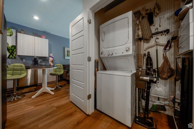 Laundry room with stacked washing machine and dryer, light wood finished floors, an office area, and recessed lighting | Image 13