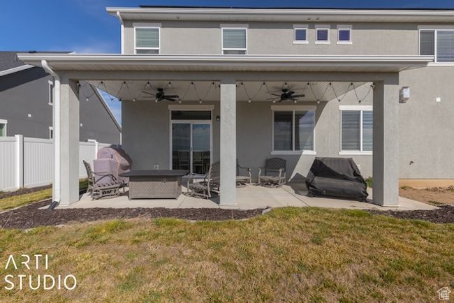 Rear view of property with ceiling fan, fence, stucco siding, a yard, and a patio | Image 45