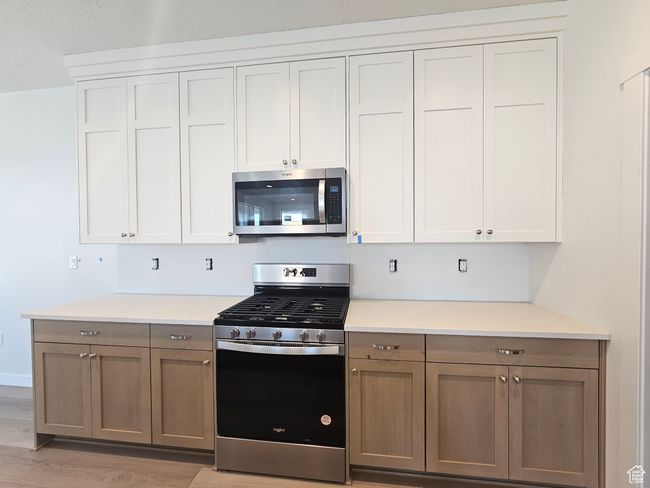Kitchen featuring stainless steel appliances, light wood finished floors, and light stone counters | Image 11