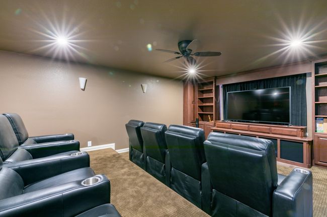 Cinema room featuring carpet, built in shelves, and a ceiling fan | Image 25