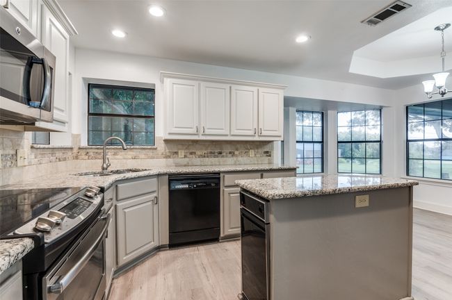 Kitchen with stainless steel appliances, light wood-type flooring, a kitchen island, tasteful backsplash, and recessed lighting | Image 10