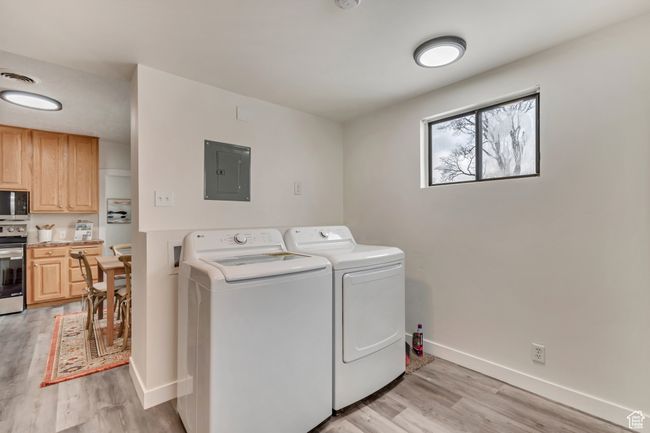 Laundry area with visible vents, baseboards, electric panel, separate washer and dryer, and light wood-style floors | Image 12