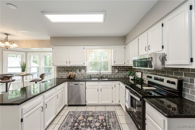 Kitchen with white cabinets, a peninsula, stainless steel appliances, and a sink | Image 5
