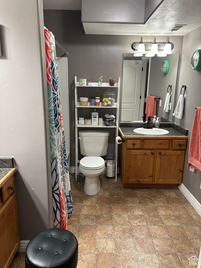 Bathroom featuring toilet, stone finish flooring, vanity, baseboards, and a shower with curtain | Image 15