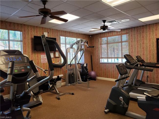Gym featuring baseboards, wooden walls, ceiling fan, and a wealth of natural light | Image 39