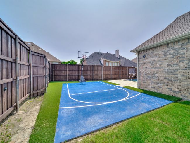 View of sport court featuring basketball hoop and a fenced backyard | Image 32