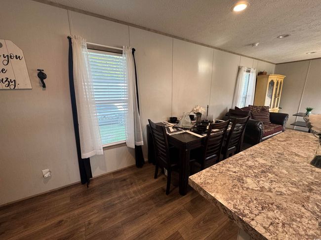 Dining room with a textured ceiling, dark wood finished floors, ornamental molding, and healthy amount of natural light | Image 8