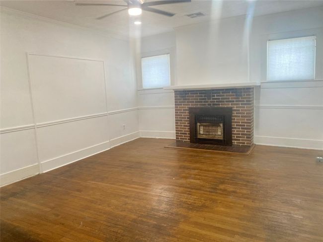 Unfurnished living room with wood finished floors, ceiling fan, a brick fireplace, and ornamental molding | Image 5