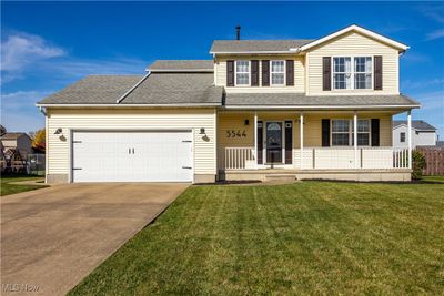 View of front of home with a front yard, a porch, and a garage | Image 1