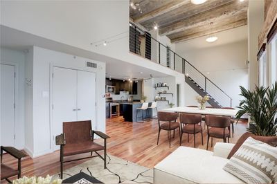 Continuing the tour, a 180-degree view showcases the kitchen, open stairway, loft area and the majestic beamed ceiling, adding character and depth to the space. To the left, you'll find the second full bathroom, offering accessibility and convenience within this thoughtfully designed home. This photo is virtually staged. | Image 1