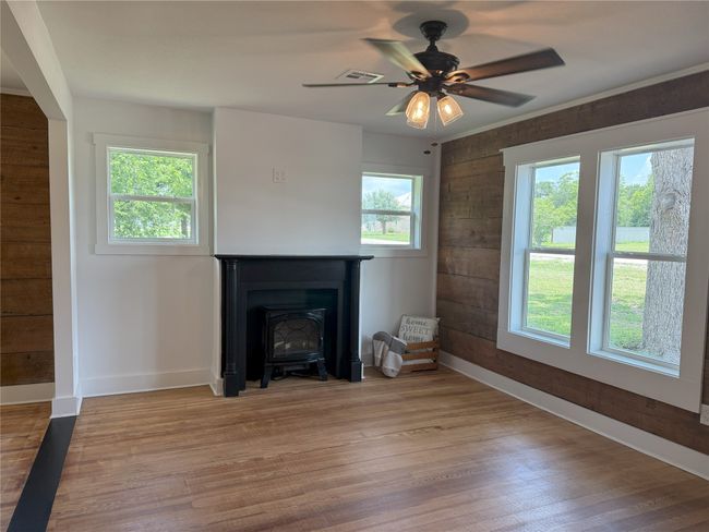 Unfurnished living room featuring healthy amount of natural light, wood finished floors, ceiling fan, and wooden walls | Image 11