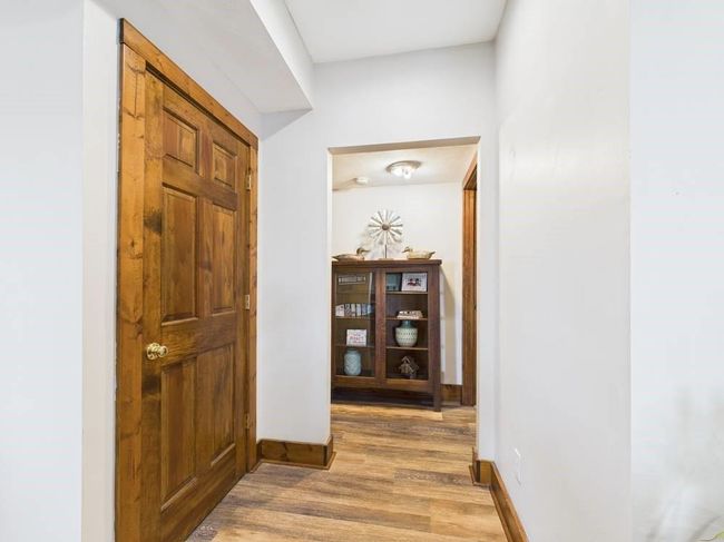 Hall featuring wood floors and baseboards showing storage below stairs and entry to 2 lower level bedrooms | Image 53