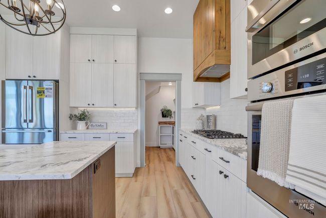 Kitchen with appliances with stainless steel finishes, light wood-type flooring, tasteful backsplash, white cabinets, and recessed lighting | Image 10
