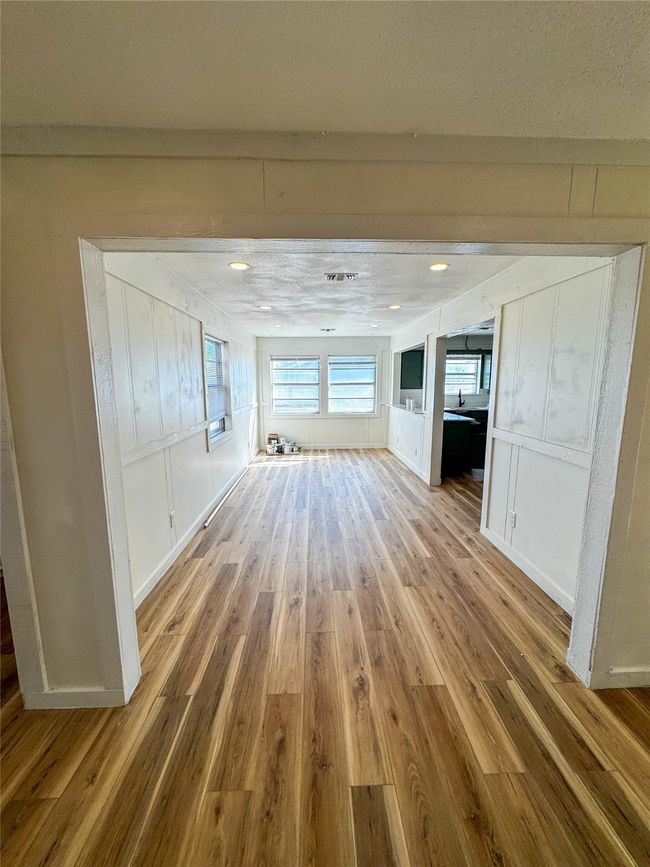 Unfurnished living room featuring a decorative wall and wood finished floors | Image 16