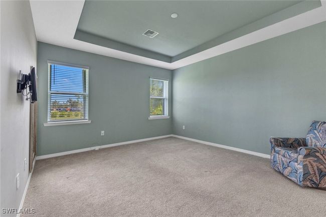 Carpeted Master Bedroom featuring visible vents, baseboards, a raised ceiling, and a healthy amount of sunlight | Image 33