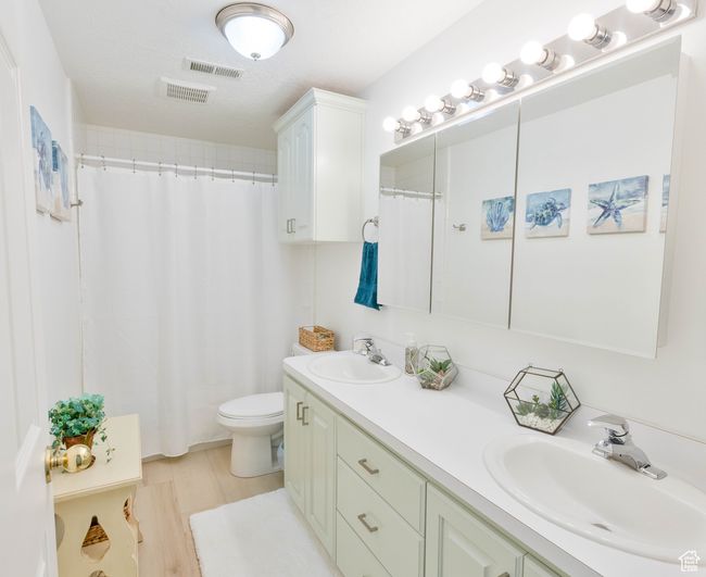 Full bath with double vanity, toilet, a shower with shower curtain, and wood finished floors | Image 39