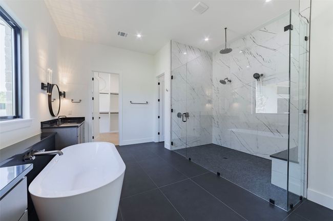 Owner's bathroom featuring a spa like walk-in shower, a freestanding soaking tub, a spacious closet, dual vanities, and recessed lighting | Image 24