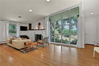 Living room featuring a fireplace, light hardwood / wood-style flooring, and a baseboard radiator | Image 3