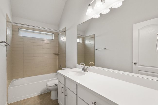 Bathroom featuring vanity, vaulted ceiling, tile patterned flooring, and shower combination | Image 20