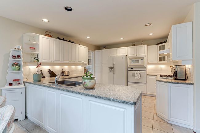 Kitchen featuring white appliances, glass insert cabinets, a peninsula, open shelves, and a sink | Image 9