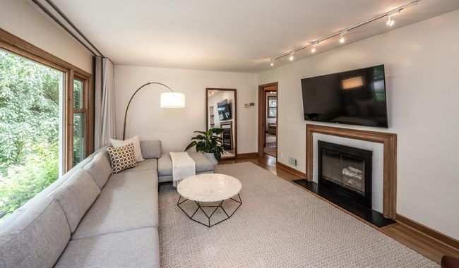 Living room with large picture window, hardwood floors & wood burning fireplace. | Image 9