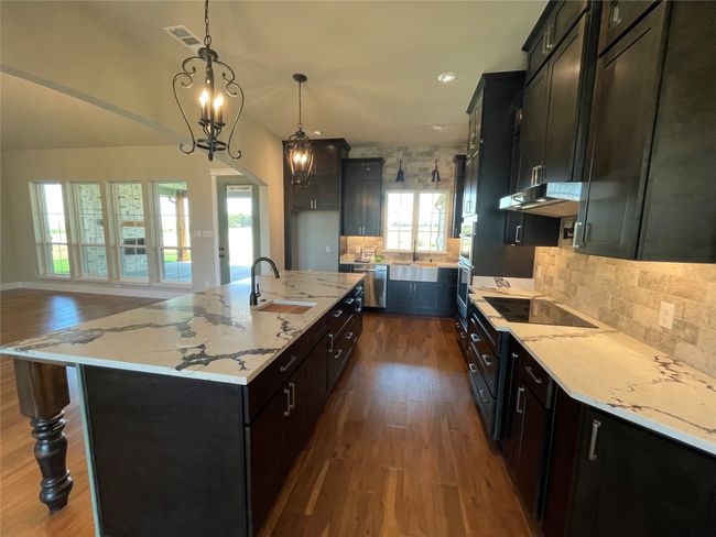 Kitchen featuring dark wood-style floors, decorative backsplash, light stone countertops, and recessed lighting | Image 8