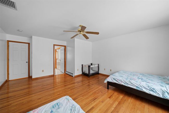 Bedroom featuring visible vents, light wood-type flooring, baseboards, a baseboard radiator, and ceiling fan | Image 26
