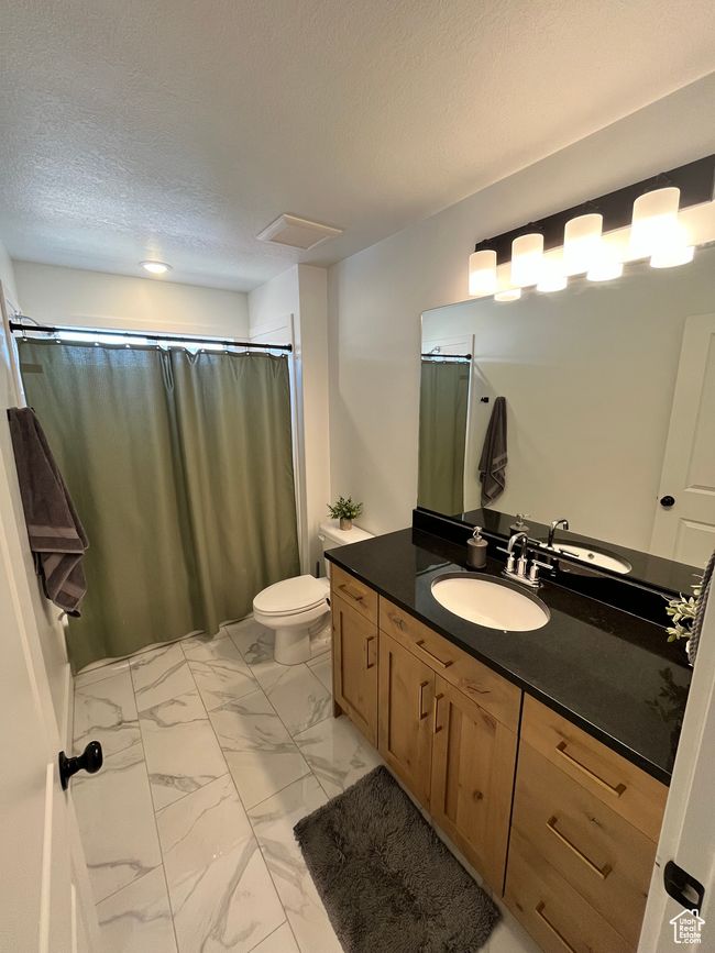 Bathroom with marble finish flooring, vanity, toilet, a shower with curtain, and a textured ceiling | Image 23