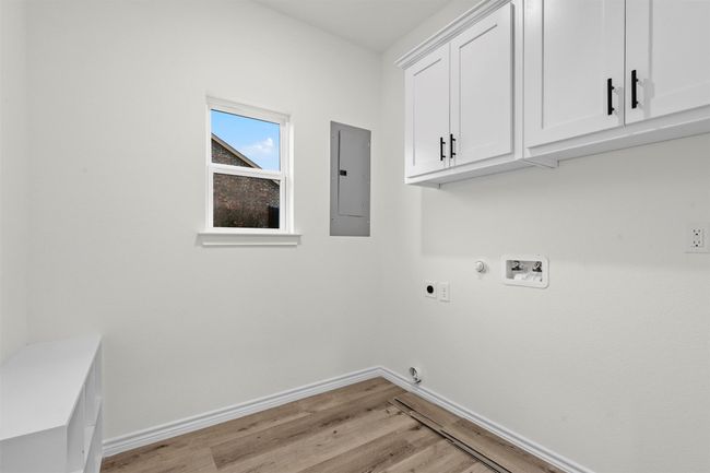 Washroom with light hardwood / wood-style flooring, electric panel, hookup for a washing machine, cabinets, and electric dryer hookup | Image 21