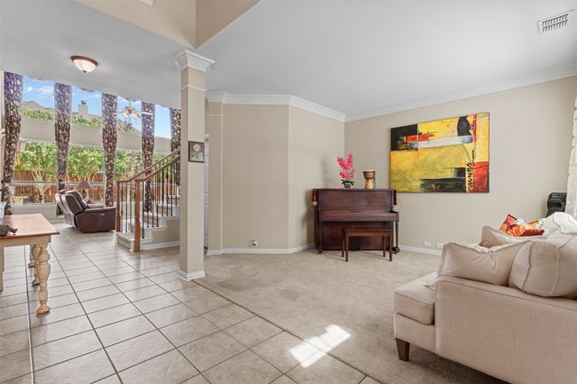 Living room with baseboards, stairs, light colored carpet, ornate columns, and crown molding | Image 7