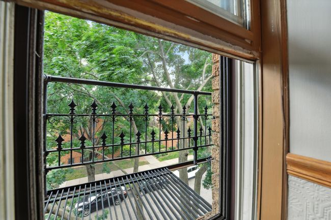 Charming neighborhood view framed by wrought-iron detail from the unit’s window. | Image 29