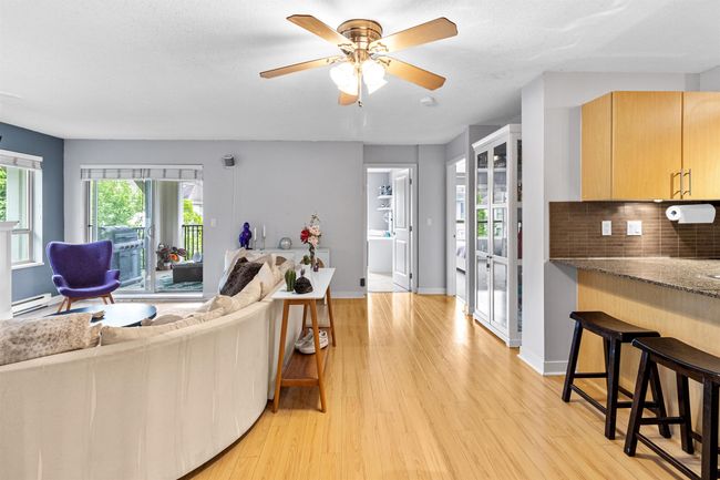 Living area featuring light wood finished floors, a baseboard heating unit, and a ceiling fan | Image 4