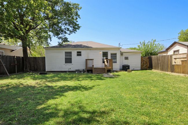 Rear view of house featuring central air condition unit, a fenced backyard, a wooden deck, and a lawn | Image 12