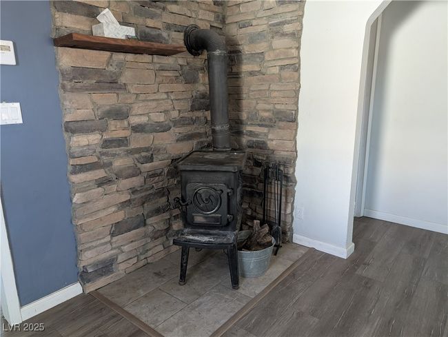 Room details featuring a wood stove, baseboards, and wood finished floors | Image 10