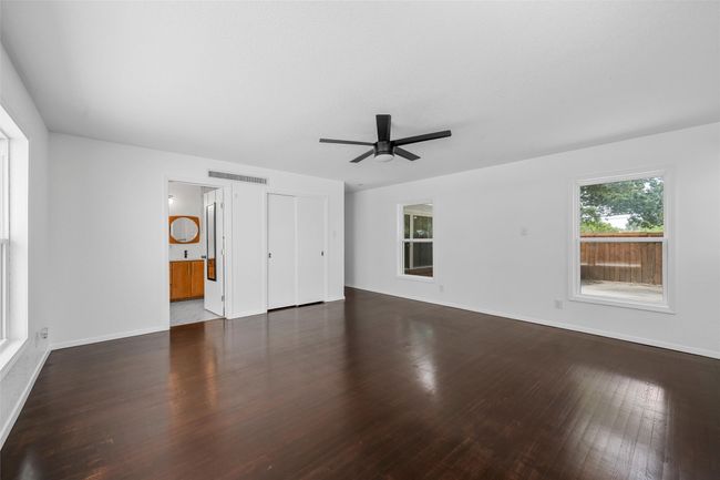 Unfurnished bedroom featuring wood finished floors, baseboards, connected bathroom, and a ceiling fan | Image 16