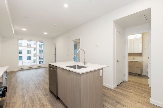Kitchen featuring a sink, modern cabinets, stainless steel dishwasher, light wood-style flooring, and a baseboard radiator | Image 11