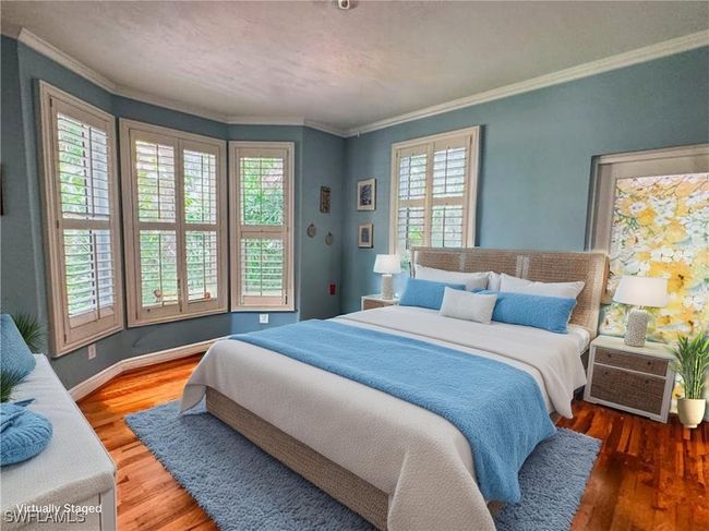 Bedroom with wood finished floors, crown molding, and baseboards | Image 12