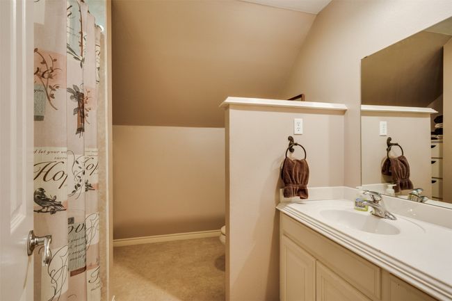 Bathroom with a shower with curtain, vaulted ceiling, vanity, and toilet | Image 30