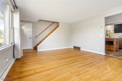 Unfurnished living room with a baseboard heating unit and light hardwood / wood-style flooring | Image 3