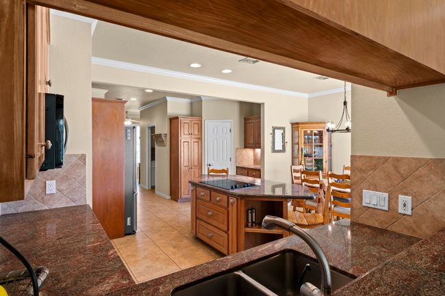 Kitchen featuring a notable chandelier, a sink, backsplash, recessed lighting, and black electric cooktop | Image 10